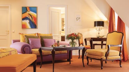 Junior suite at the Hotel Bulow Palais with an orange colour scheme, sofa, arm chair and double bed 