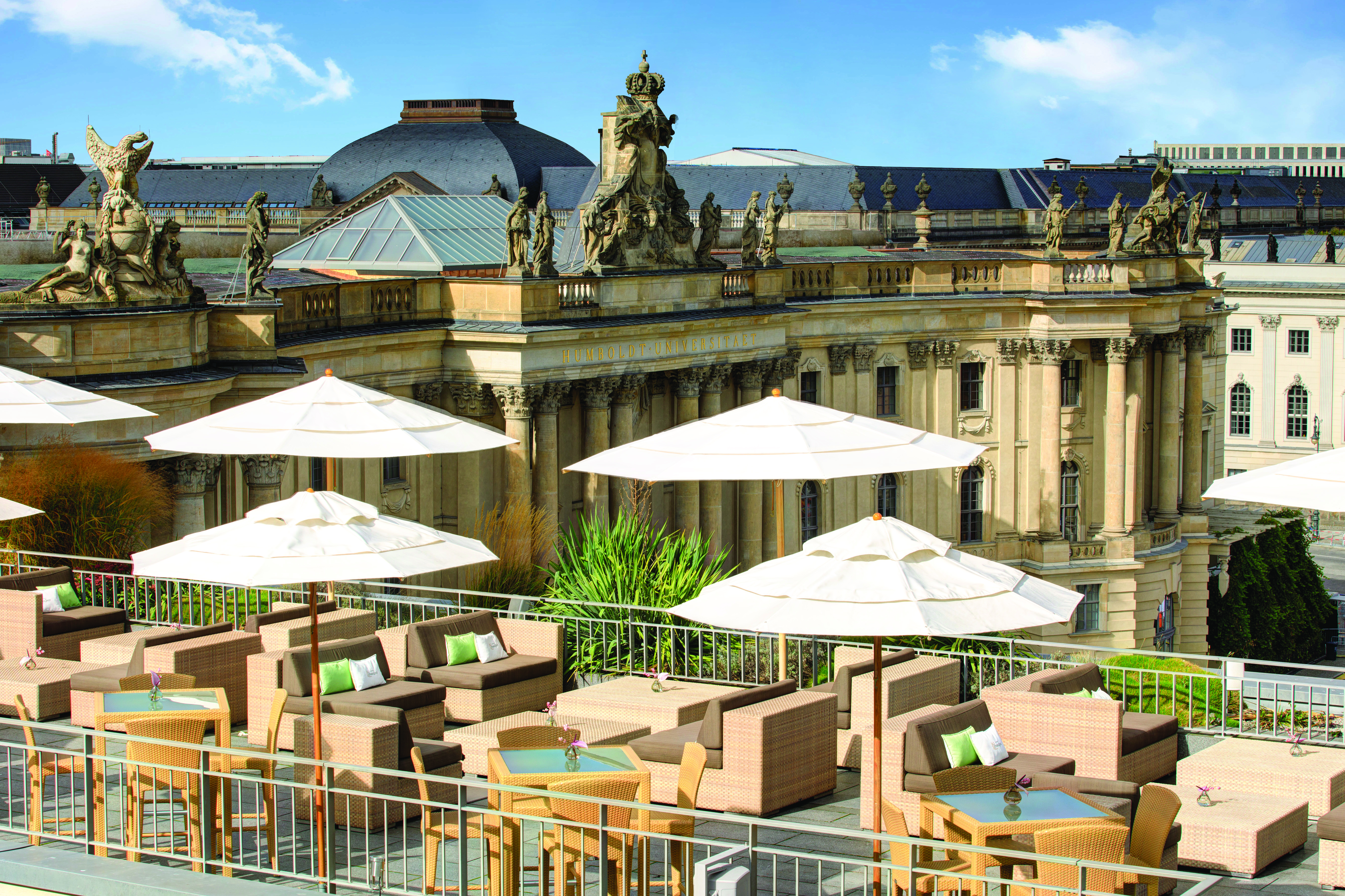 Hotel de Rome Berlin rooftop terrace with sofas and umbrellas overlooking large building overlooking the opera house