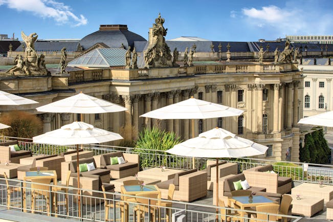 Hotel de Rome Berlin rooftop terrace with sofas and umbrellas overlooking large building overlooking the opera house