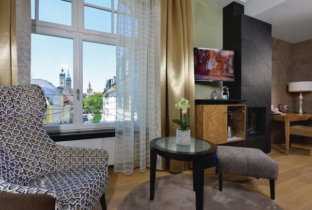 Hotel Torbrau Munich junior suite armchair table desk and telephone window with a city view