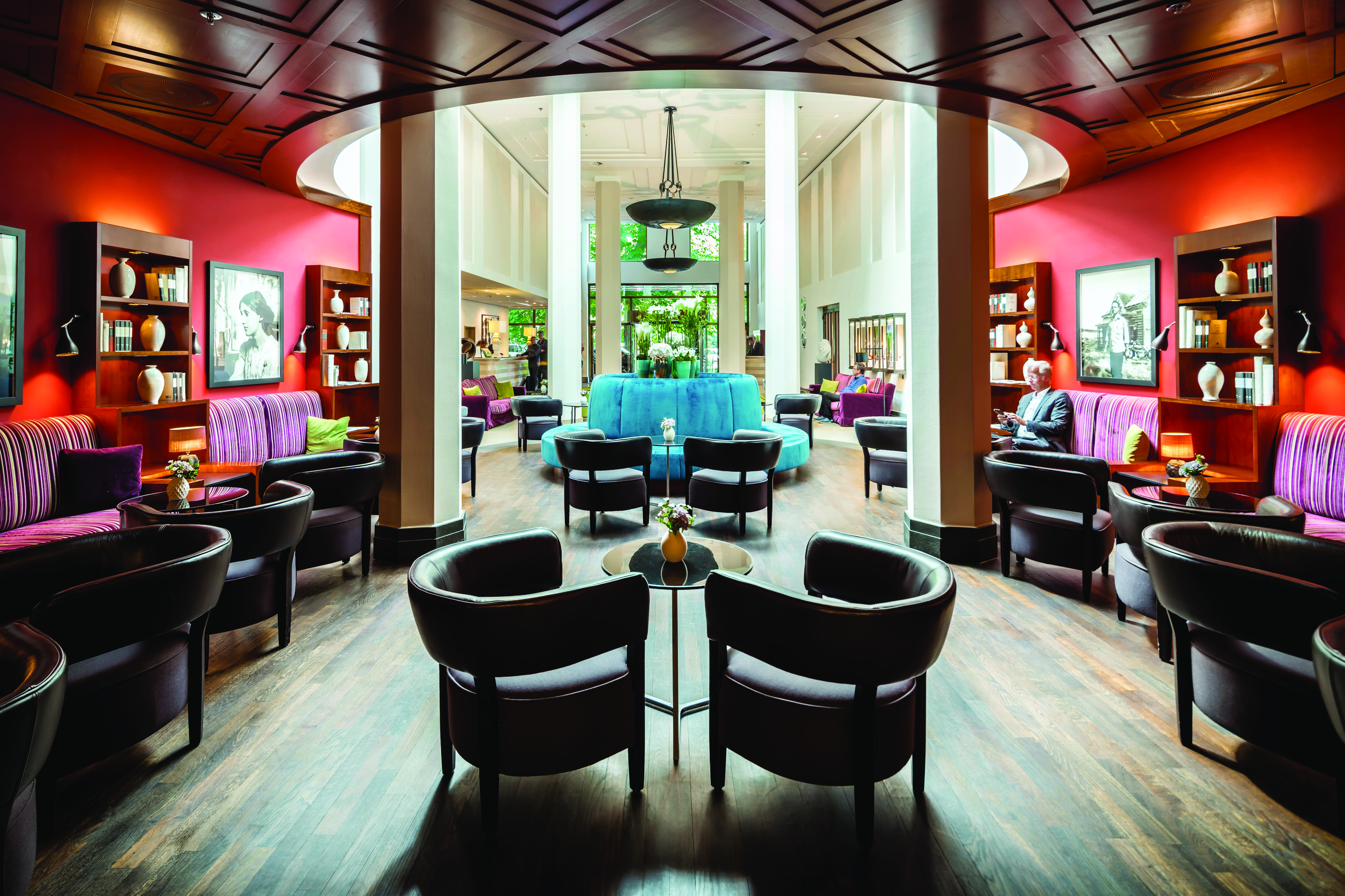 Lobby area at the Charles hotel with leather seating areas, wooden pannels and a reception desk in the distance