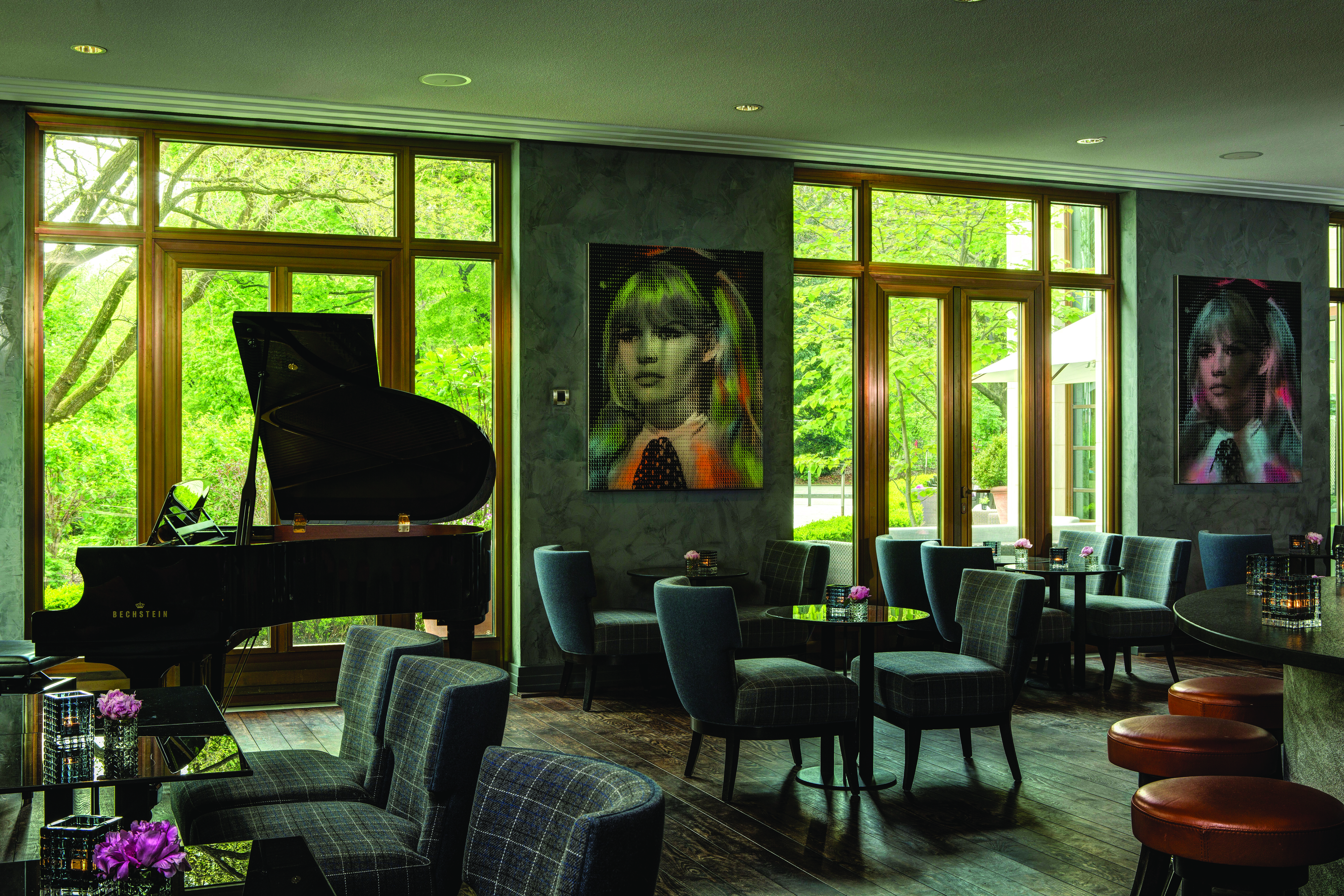 Lounge area at the Charles Hotel with seating areas set up, a piano in the corner and modern pieces of art on the wall