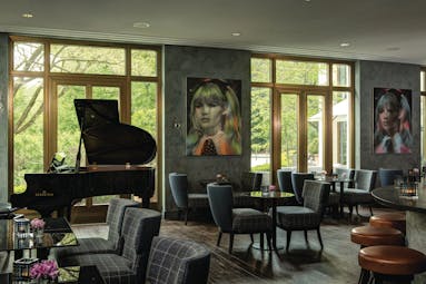 Lounge area at the Charles Hotel with seating areas set up, a piano in the corner and modern pieces of art on the wall
