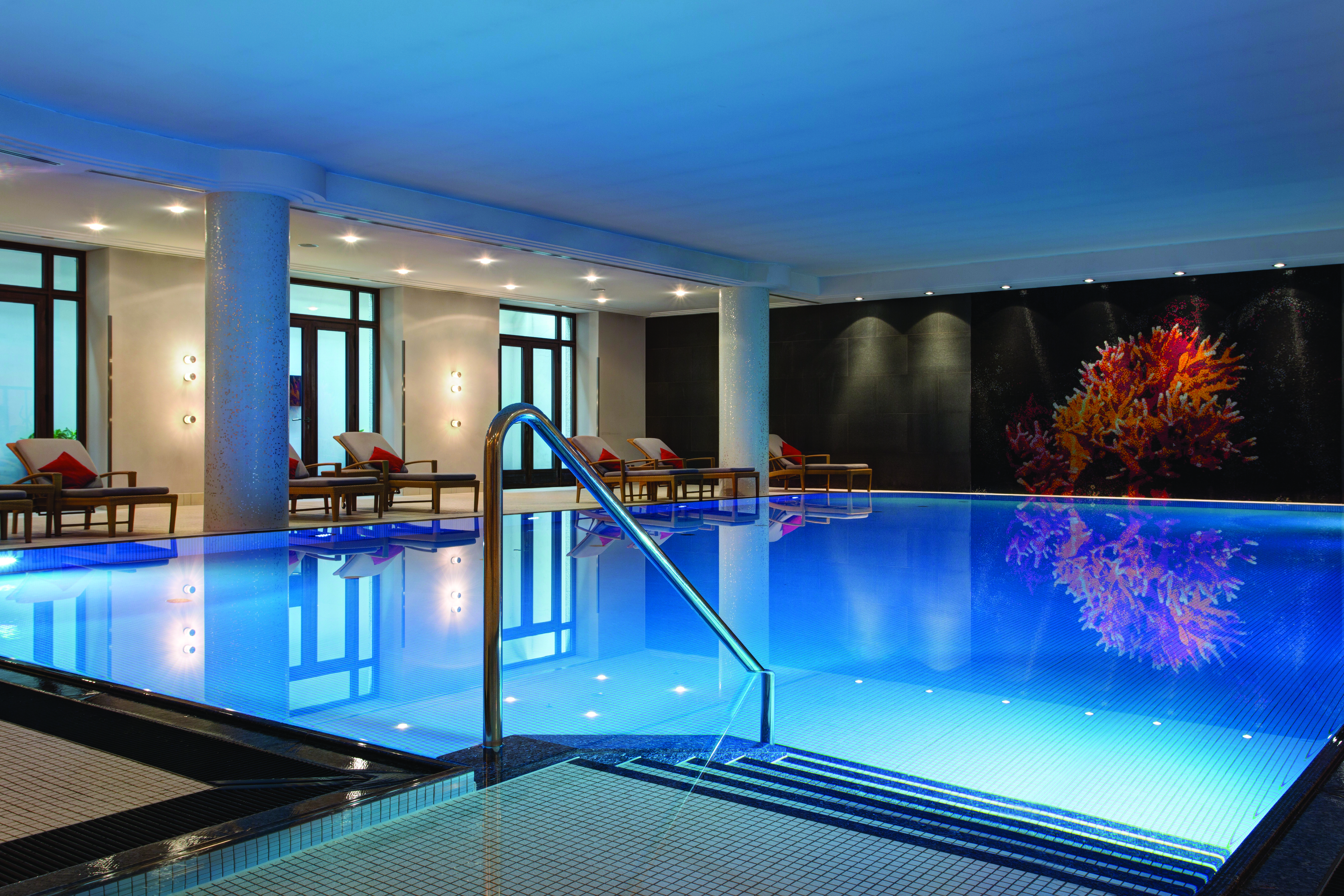 Pool and spa at the Charles Hotel Munich with steps leading into a pool with little lights lighting up the bottom 