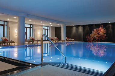 Pool and spa at the Charles Hotel Munich with steps leading into a pool with little lights lighting up the bottom 
