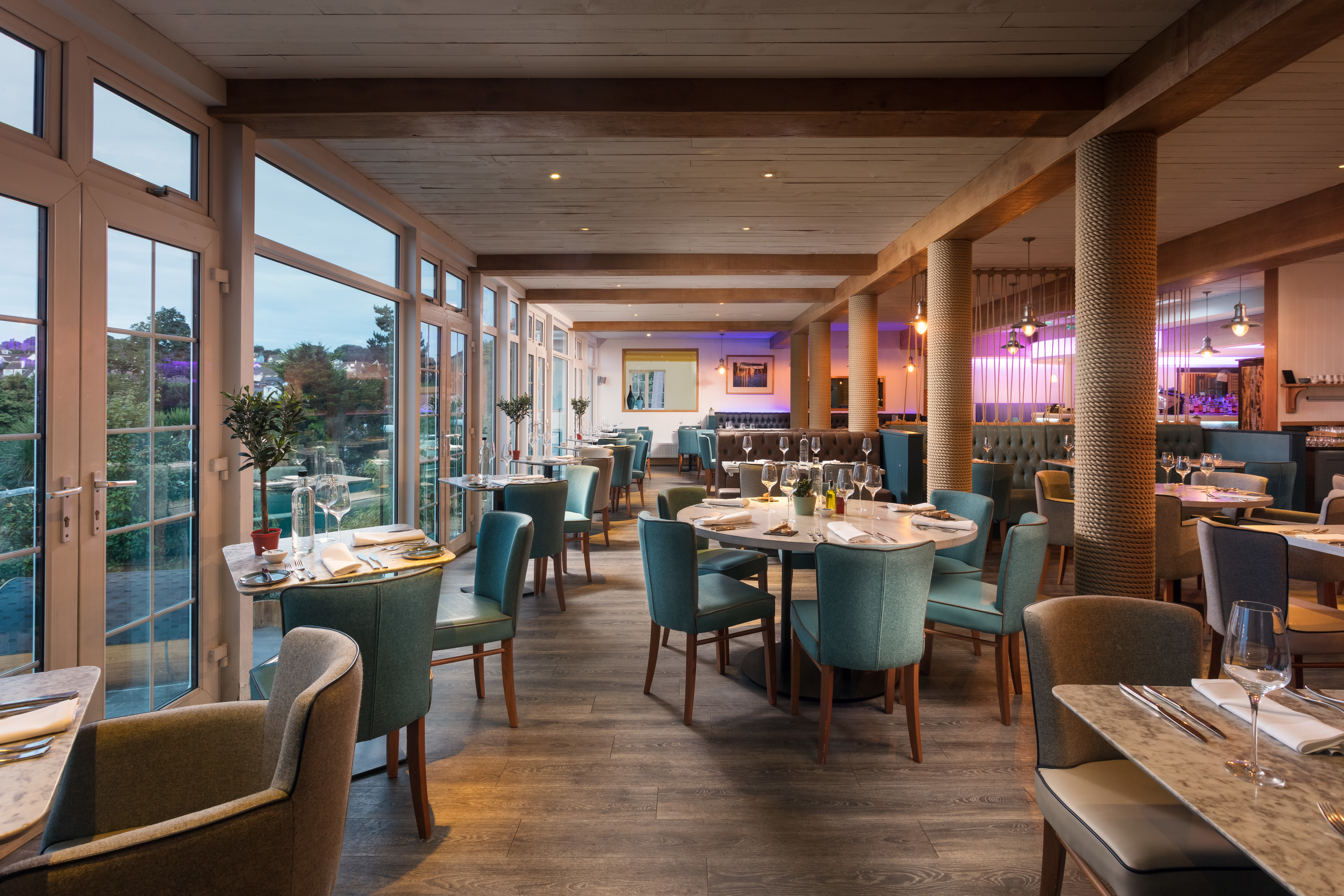 Smart restaurant with wooden floors and long windows, green chairs and views of garden at St Michaels Resort