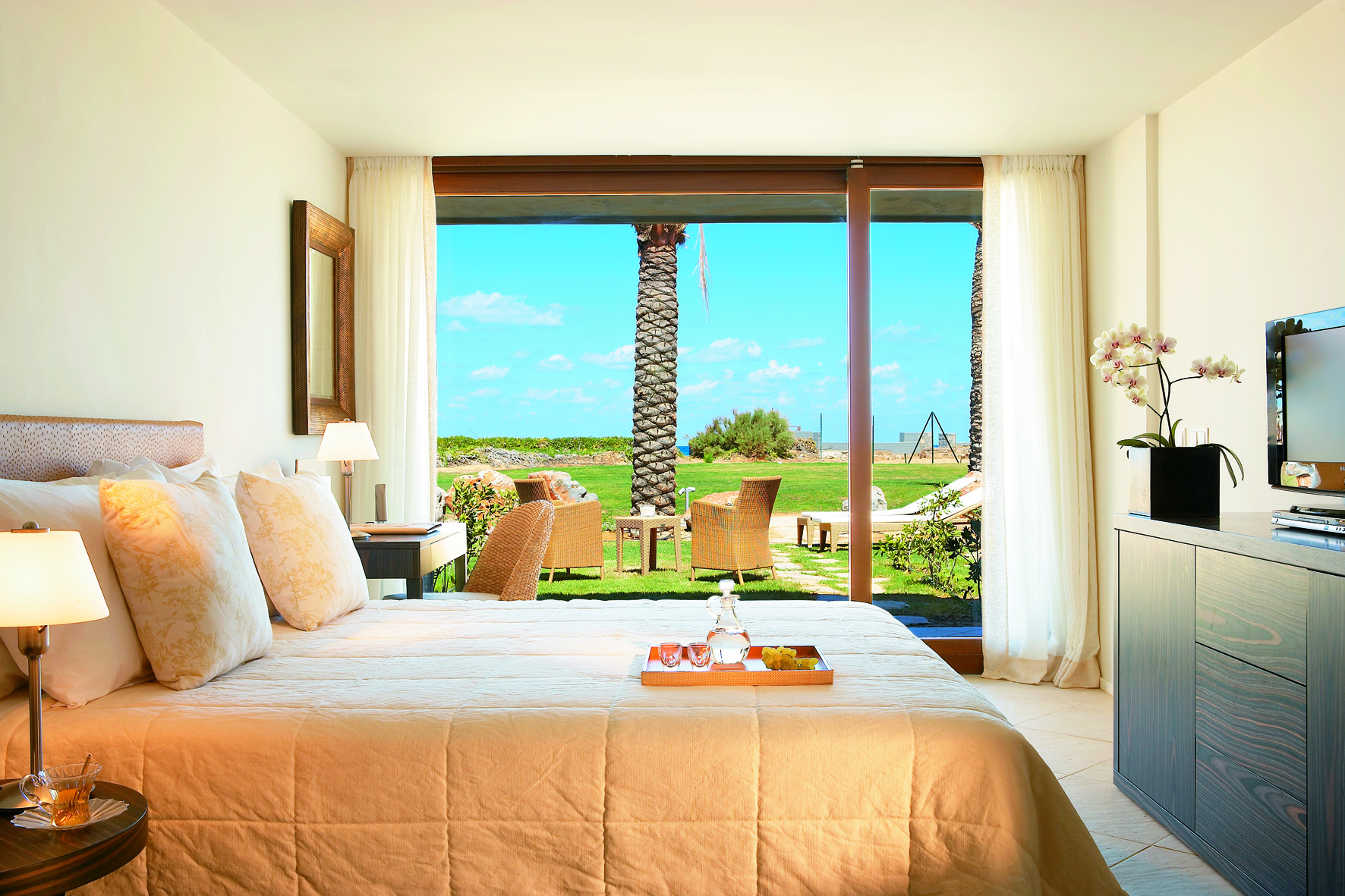 Amirandes bedroom with a view of the gardens, large double bed and television with minimalist decor 