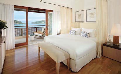 Blue Palace Greece bedroom with curtains round bed and balcony with sea view
