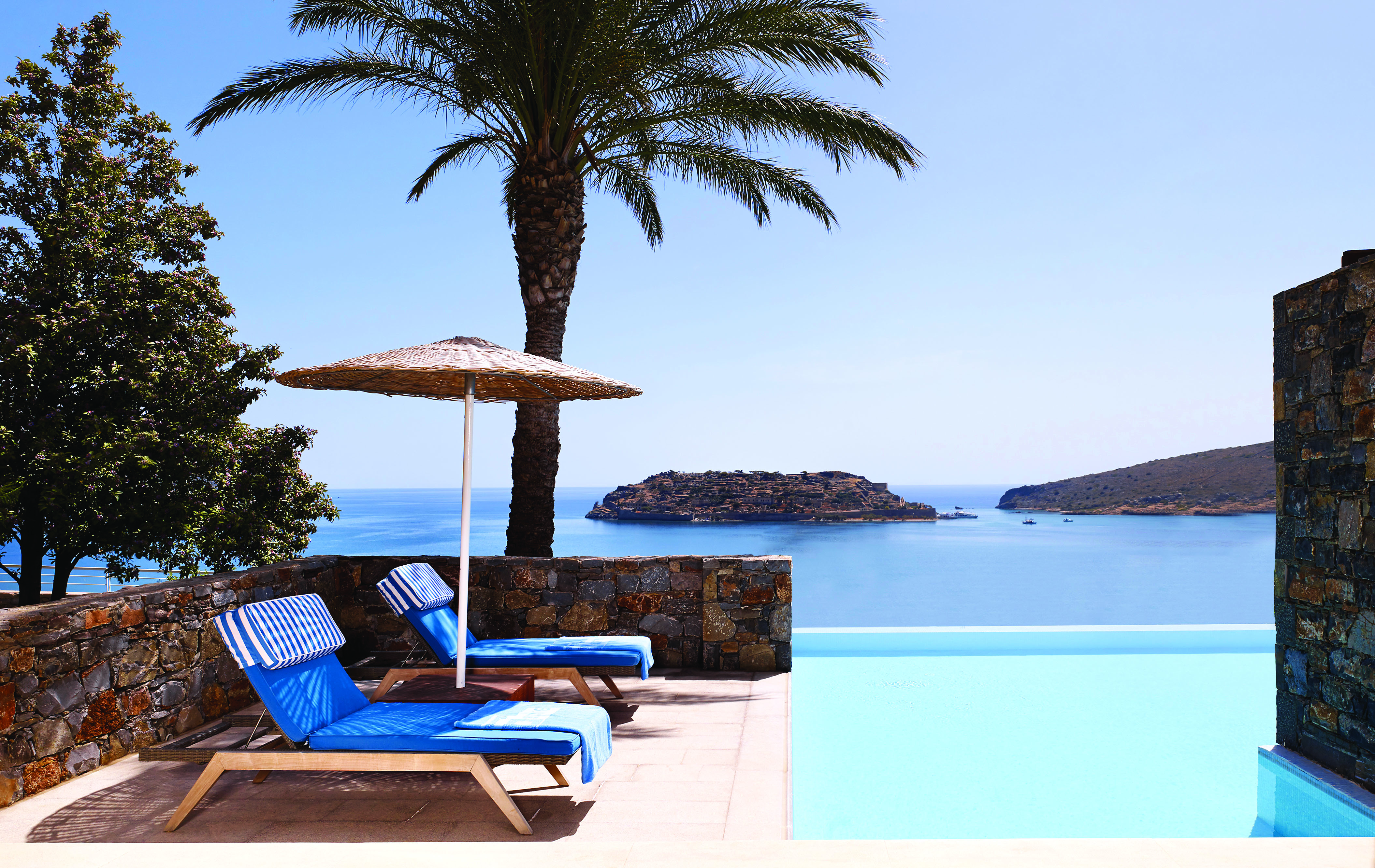 Blue Palace Greece outdoor pool loungers and sea view