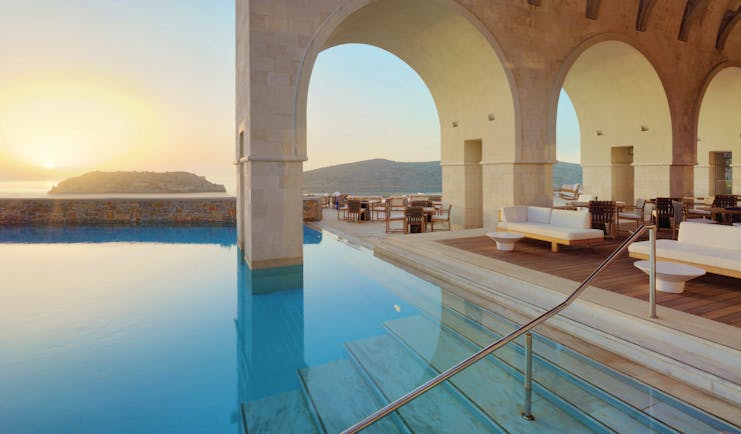Blue Palace Greece outdoor pool decked seating area with large archways