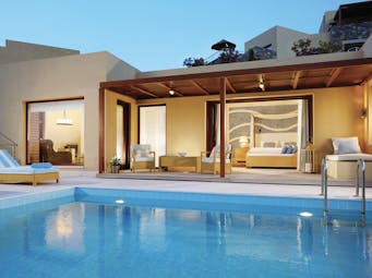 Blue Palace Greece suite pool sitting room with large windows and outdoor swimming pool with lounger