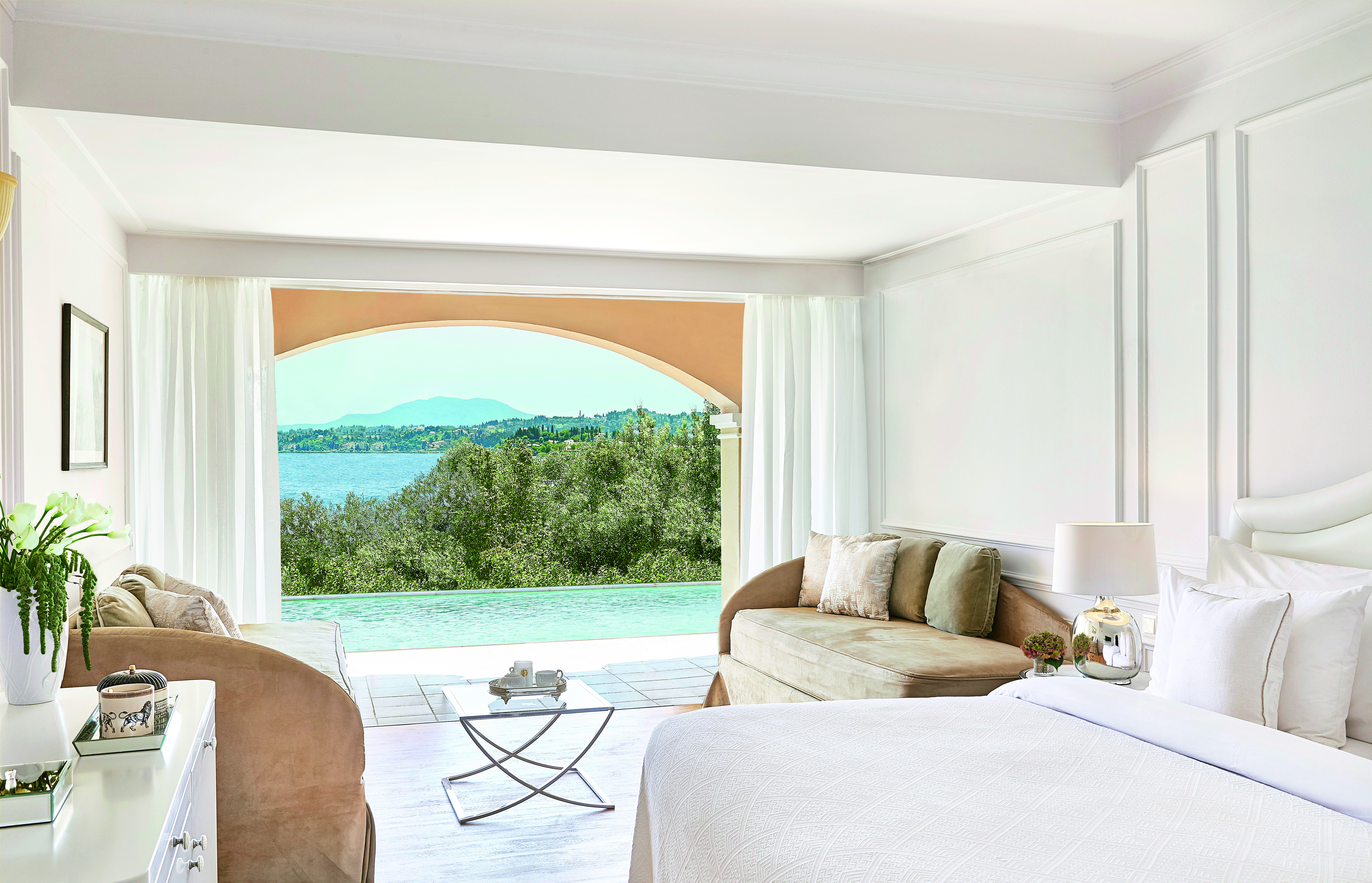 White room with open doors and pool and sea views Corfu Imperial