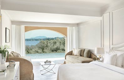 White room with open doors and pool and sea views Corfu Imperial