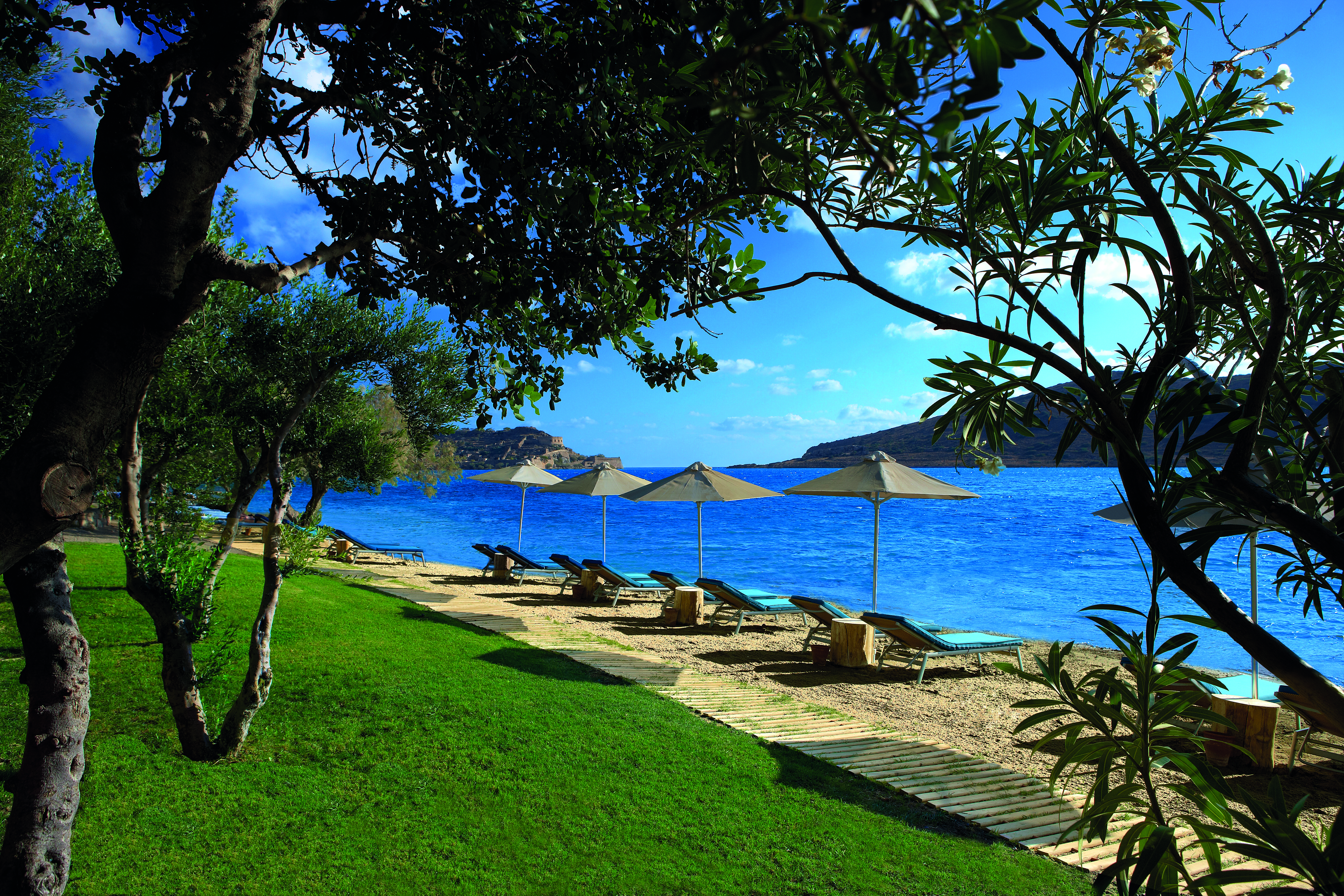 Domes of Elounda Greece beach with sun loungers and umbrellas