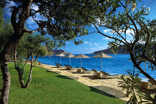 Domes of Elounda Greece beach with sun loungers and umbrellas