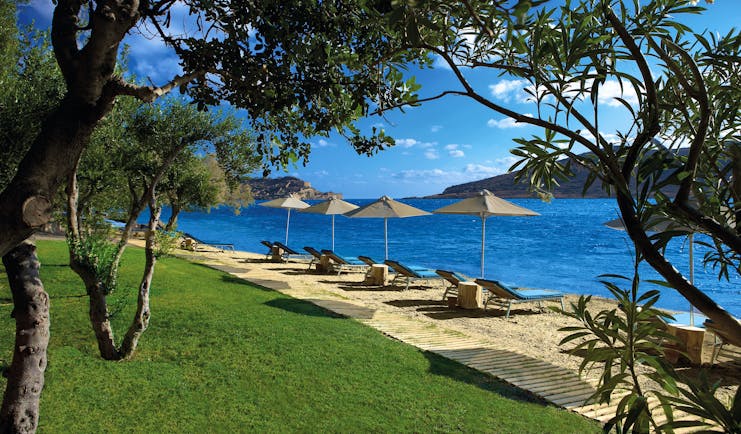 Domes of Elounda Greece beach with sun loungers and umbrellas