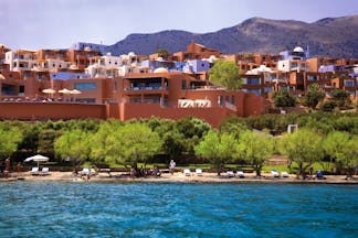 Domes of Elounda Greece exterior panorama several terracotta buildings near hills and a beach