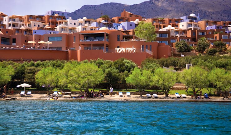 Domes of Elounda Greece exterior panorama several terracotta buildings near hills and a beach