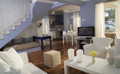 Domes of Elounda Greece living room with sofa and chairs television and a white staircase