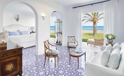 Grecotel Caramel Greece  beach villa bedroom with blue and white tiled floor sitting area and doors opening to garden 