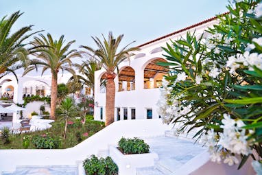 Grecotel Caramel Greece exterior white building with archways and palm trees