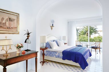 Grecotel Caramel Greece junior suite bedroom with blue and white tiled floor and balcony
