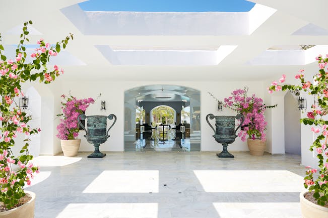 Grecotel Caramel Greece lobby area with large grey urns and pink flowers