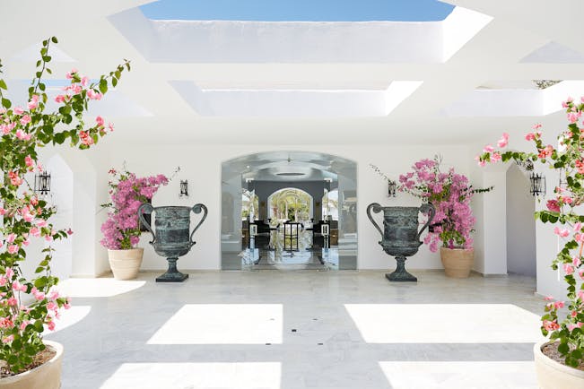 Grecotel Caramel Greece lobby area with large grey urns and pink flowers