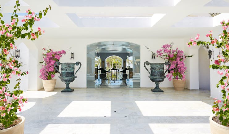 Grecotel Caramel Greece lobby area with large grey urns and pink flowers