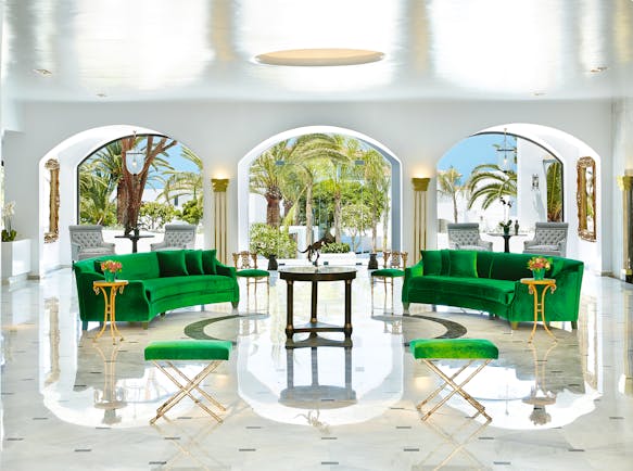 Grecotel Caramel Greece lounge area with two green sofas and archways with palm trees