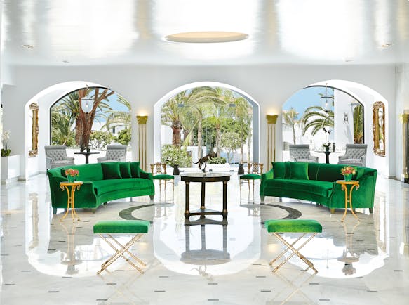 Grecotel Caramel Greece lounge area with two green sofas and archways with palm trees