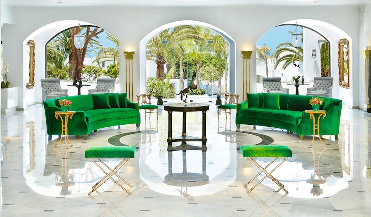 Grecotel Caramel Greece lounge area with two green sofas and archways with palm trees