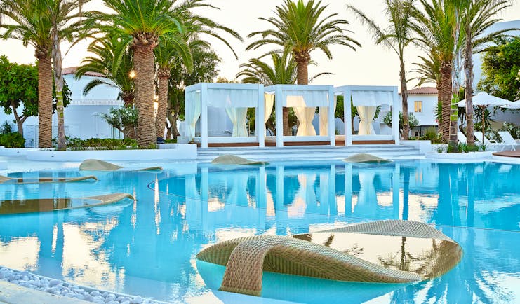 Grecotel Caramel Greece outdoor pool with leaf shape loungers in pool and canopied loungers