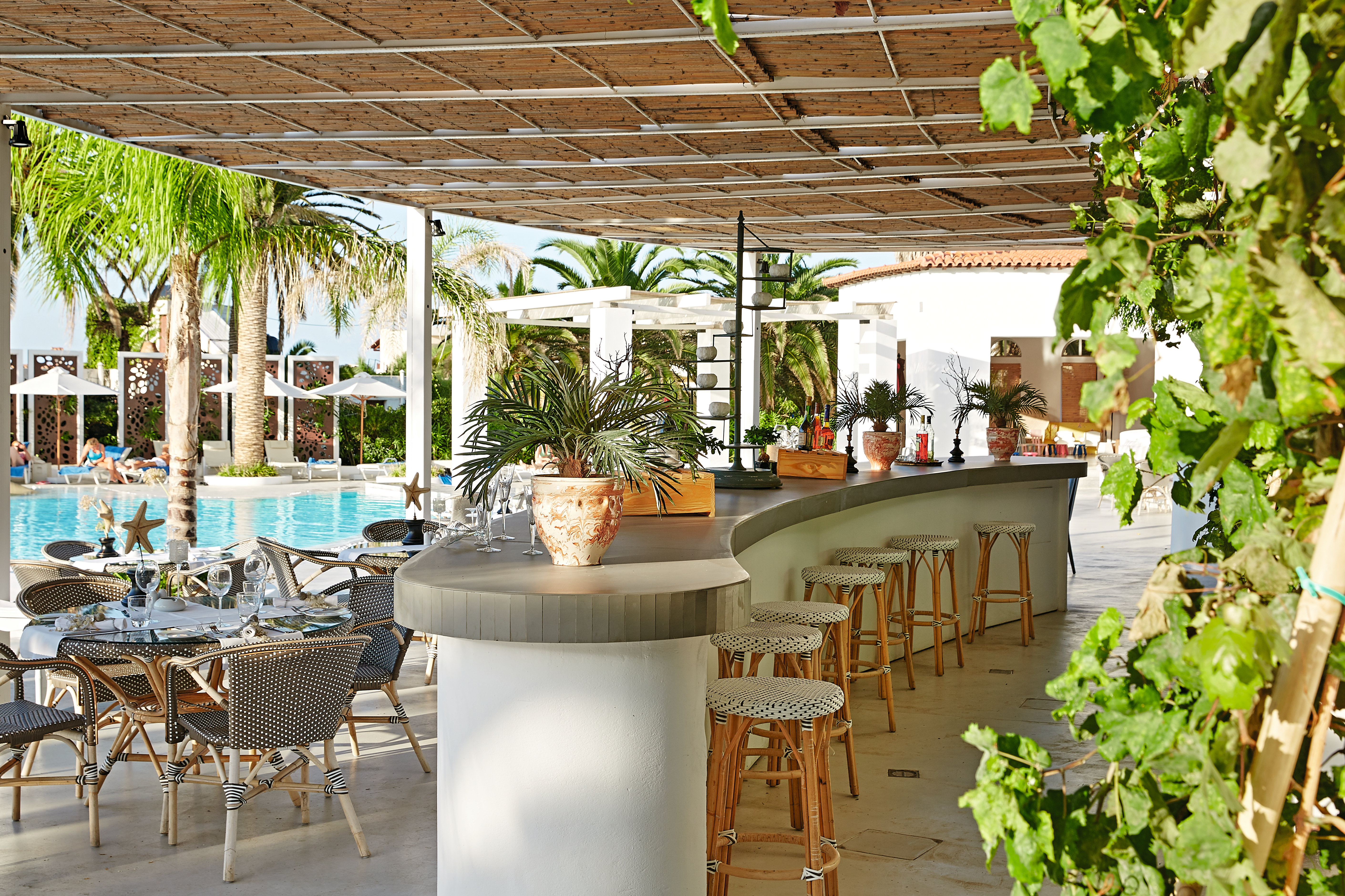 Grecotel Caramel Greece pool lounge area with bar outdoors