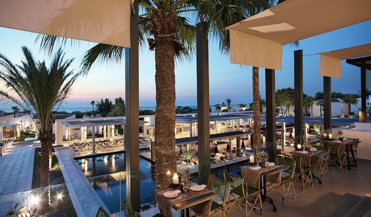 Evening shot of restaurant with palms overlooking the pool