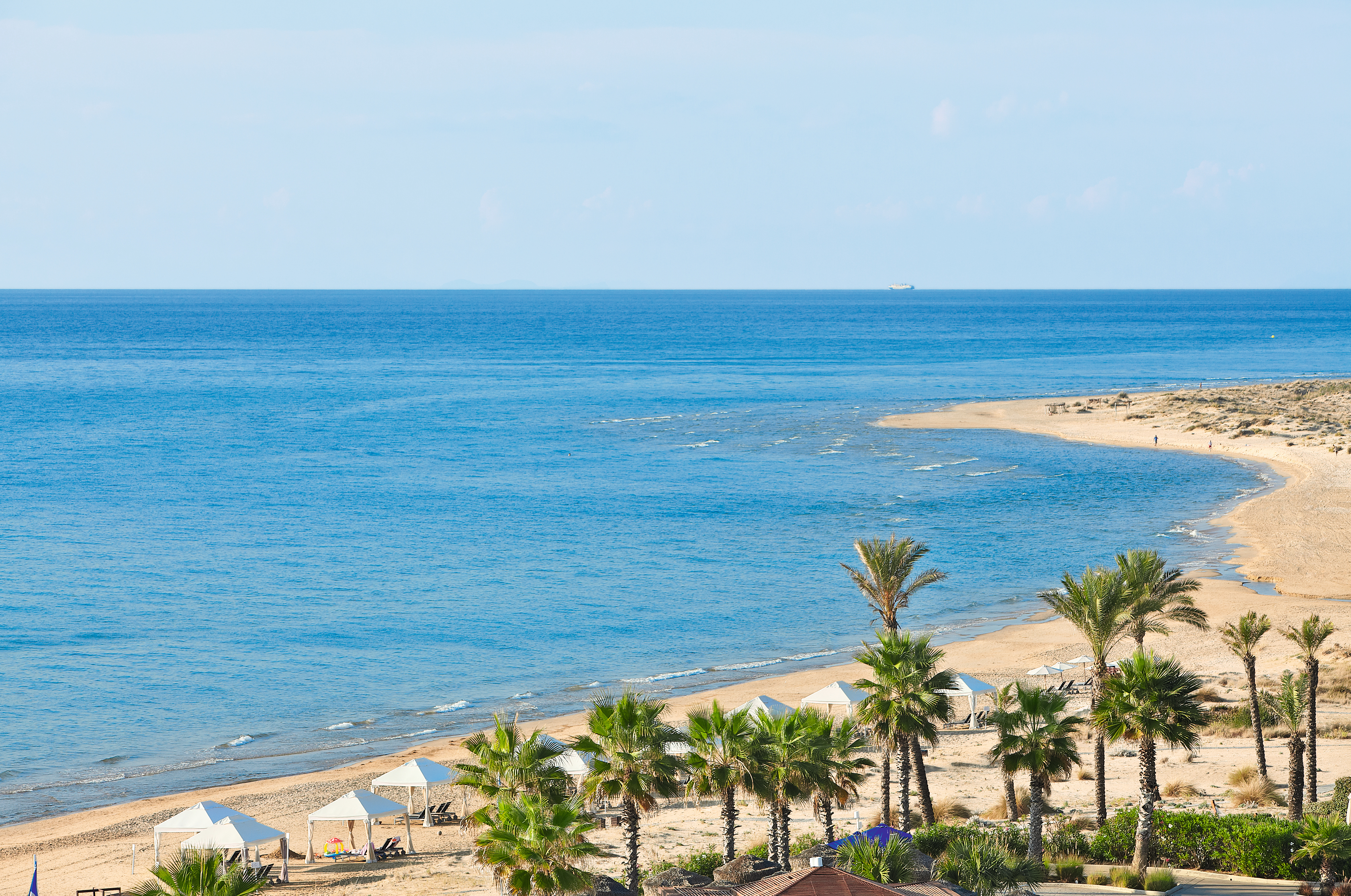 Grecotel Mandola Rosa Greece beach view with white pergolas and palm trees