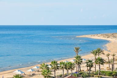 Grecotel Mandola Rosa Greece beach view with white pergolas and palm trees