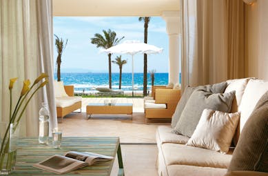 Grecotel Mandola Rosa Greece beach villa sitting area with open doors onto terrace and beach