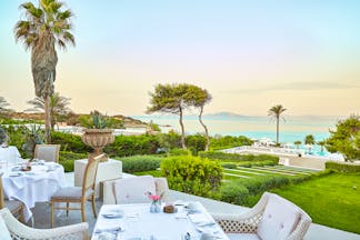 Grecotel Mandola Rosa Greece outdoor dining area overlooking lawn and sea