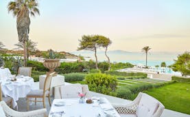 Grecotel Mandola Rosa Greece outdoor dining area overlooking lawn and sea