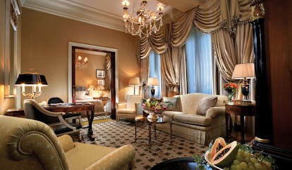 Hotel Grande Bretagne Greece suite sitting room opulent decor armchairs sofa chandelier archway to bedroom