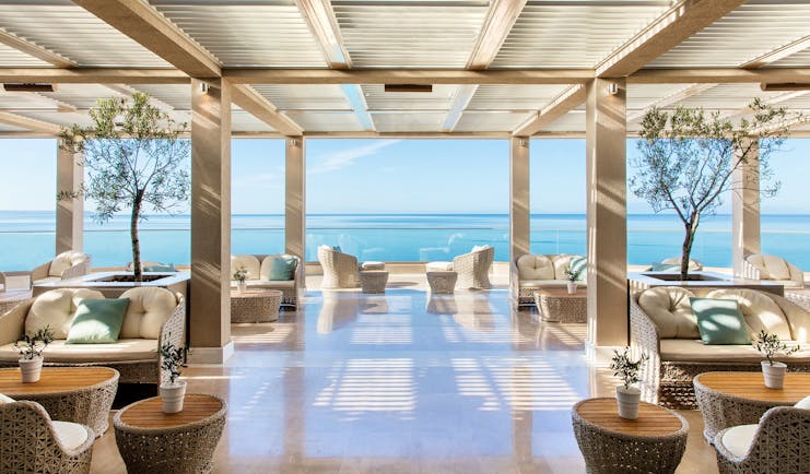 Ikos Oceania Greece veranda restaurant outdoor lounge area with large windows and sea views