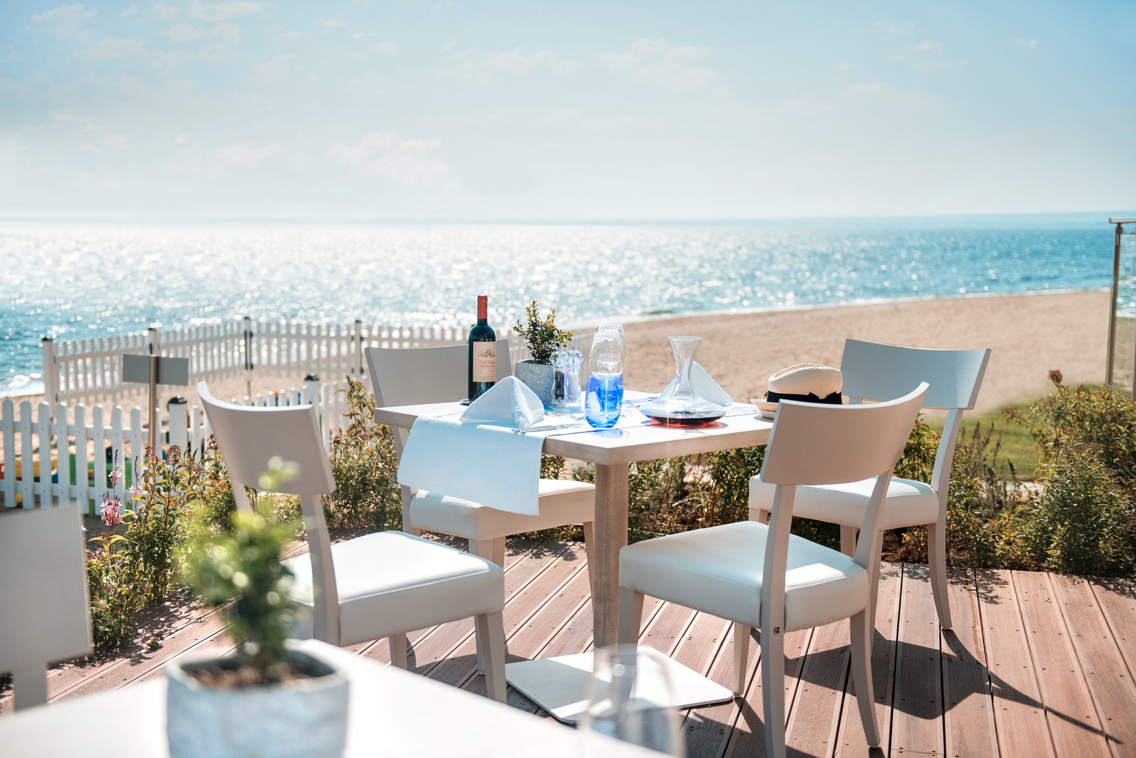 Fresco italian restaurant at the Ikos Olivia, showing an outdoor seating area on wooden decking, overlooking the beach and sea