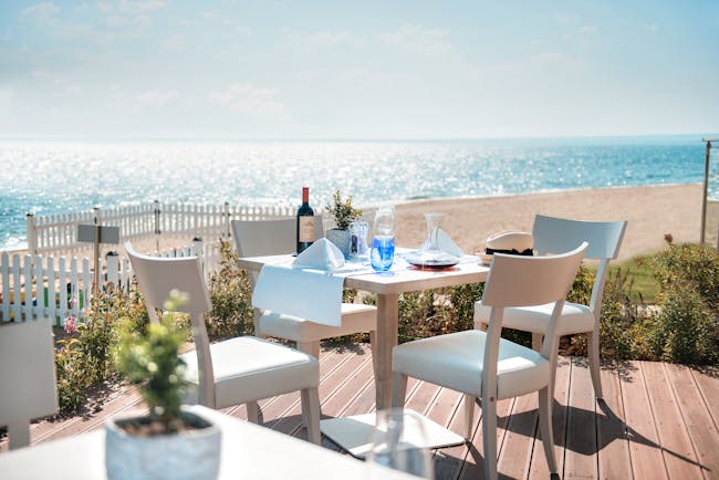 Fresco italian restaurant at the Ikos Olivia, showing an outdoor seating area on wooden decking, overlooking the beach and sea