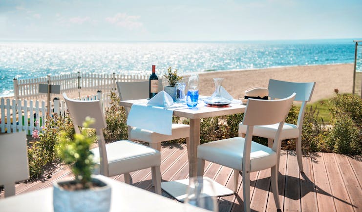 Fresco italian restaurant at the Ikos Olivia, showing an outdoor seating area on wooden decking, overlooking the beach and sea