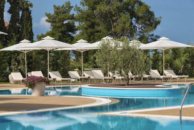 Main pool at the Ikos Olivia with white sun beds and umbrellas set up surrounding it