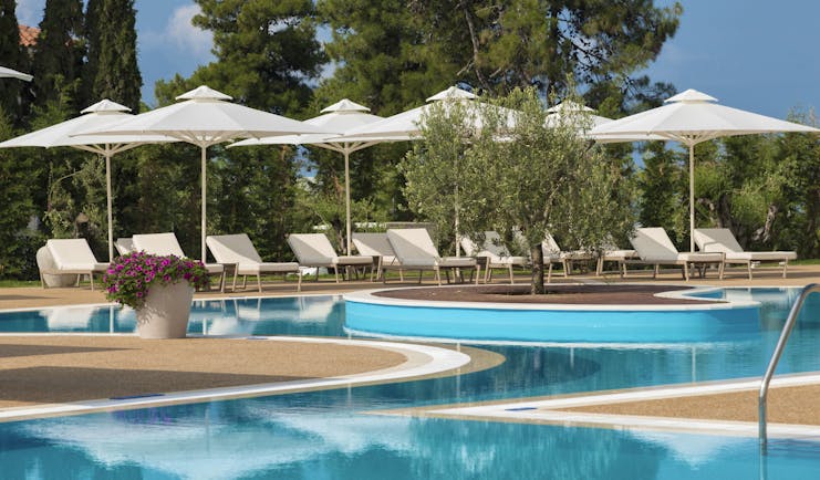 Main pool at the Ikos Olivia with white sun beds and umbrellas set up surrounding it