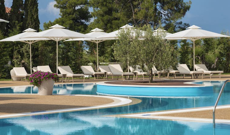 Main pool at the Ikos Olivia with white sun beds and umbrellas set up surrounding it
