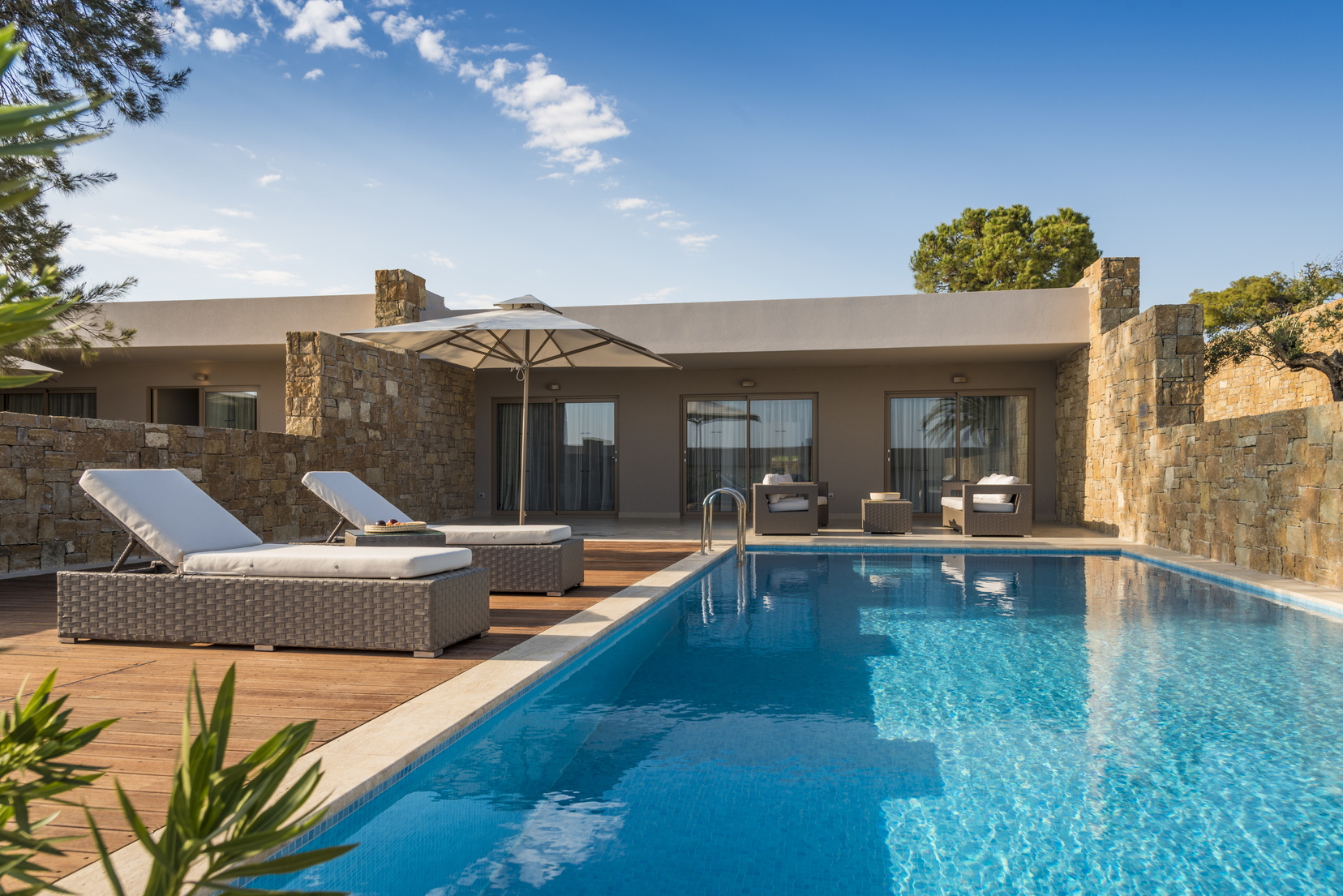 Exterior of a deluxe two bedroom bungalow suite at the Ikos Olivia showing a private pool with deck chairs around the edge