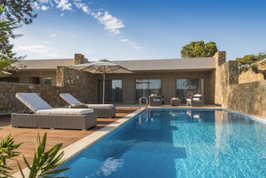 Exterior of a deluxe two bedroom bungalow suite at the Ikos Olivia showing a private pool with deck chairs around the edge